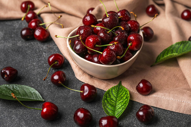 Bowl of tasty cherries with water drops on dark background - Fotó, kép