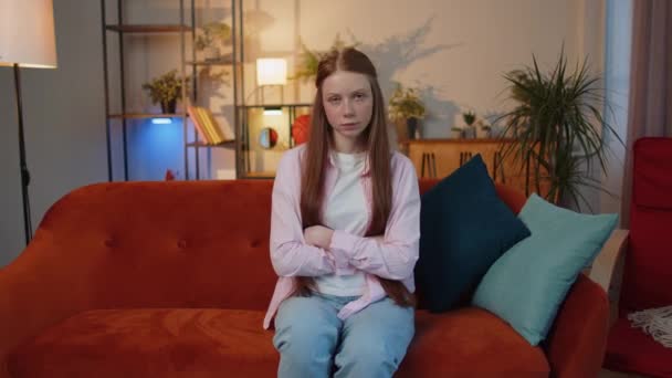 Displeased upset young redhead child girl reacting to unpleasant awful idea, dissatisfied with bad quality, wave hand, shake head No, dismiss idea, dont like proposal at home. Kid sitting on couch - Materiał filmowy, wideo