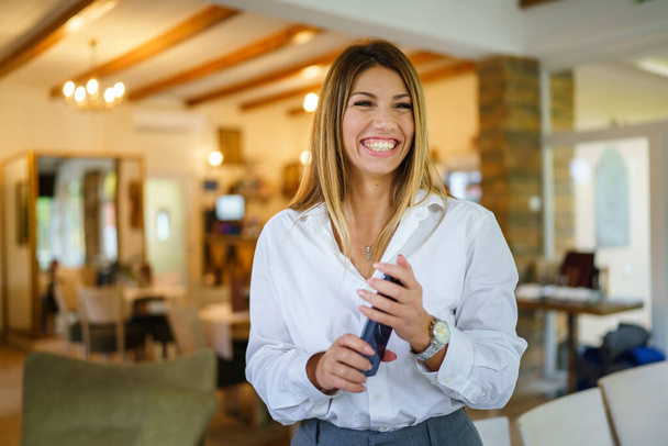 Una donna caucasica donna d'affari sorridente in piedi al ristorante in possesso di telefono cellulare Entrepreneur manager concetto moderno - Foto, immagini