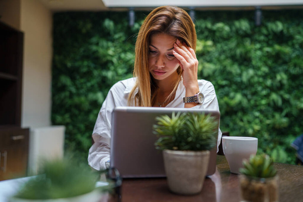 Egy nő kaukázusi üzletasszony hosszú hajjal dolgozik számítógép laptop étteremben vagy szálloda menedzser vállalkozó modern életmód koncepció - Fotó, kép