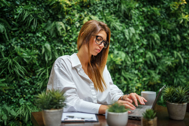 Eine kaukasische Geschäftsfrau mit langen Haaren und Brille arbeitet am Computer-Laptop Manager Unternehmer modernes Lifestylekonzept - Foto, Bild