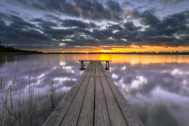 lila Sonnenuntergang über dem ruhigen See mit Holzsteg - Foto, Bild
