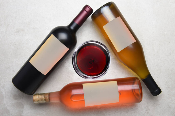 Cabernet, Rose, Chardonnay: Overhead view of a group of three different bottles with blank labels arranged in a triangle with a glass of wine in the middle. - Valokuva, kuva