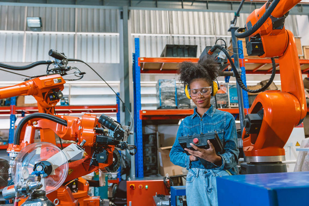 Engenheiro trabalhador mulher inteligente trabalhando programando máquina de solda robótica. preto teen menina trabalho com antecedência moderna fábrica. - Foto, Imagem