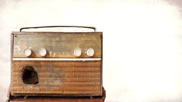 A very old, damaged radio player with an old picture background. - Foto, imagen