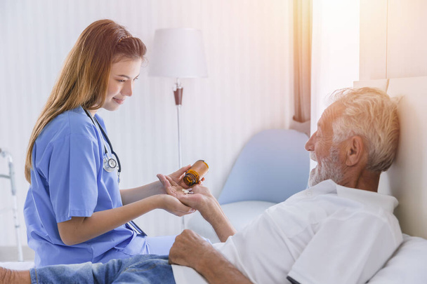 oudere man senior mensen lag op bed gezondheidszorg het geven van medicijnen pillen van verpleegkundige thuis - Foto, afbeelding