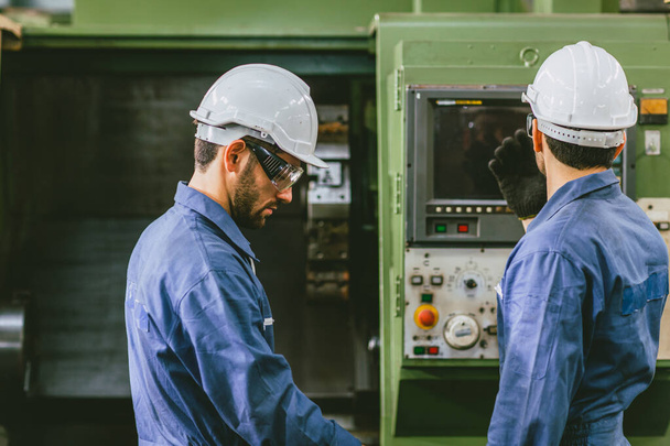 Erfahrene Ingenieure Mitarbeiter arbeiten zusammen in Metallfabrik betreiben Setup-CNC-Maschine. - Foto, Bild