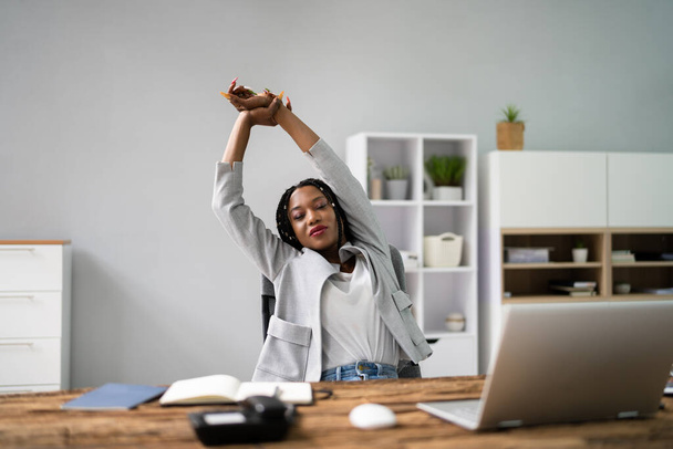 Young Businesswoman Stretching Her Arms With Laptop On Desk - Photo, image
