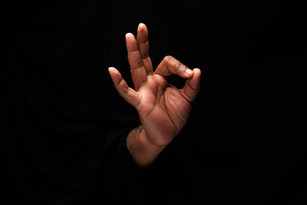 Азиатский мужчина с темной кожей одной руки кулаком пальца на черном фоне Хорошо знак пальца  - Фото, изображение