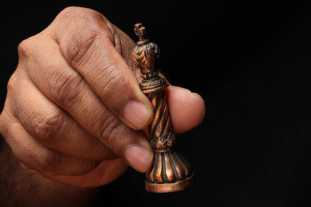 Азиатский мужчина с темной кожей одной руки кулаком палец на черном фоне проведение игры металл шахматы король - Фото, изображение