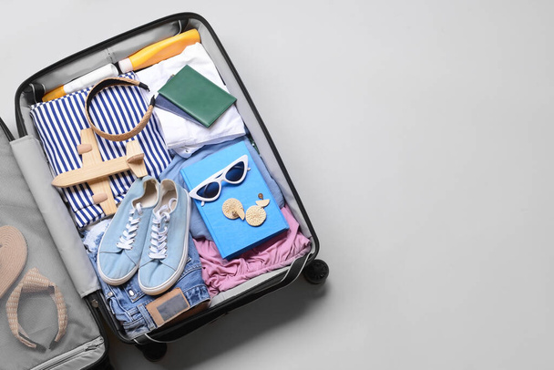 Opened suitcase with different accessories for travelling on grey background - Photo, Image