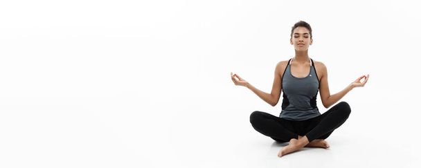 Pořádku a Fitness koncept - krásná americká Africká dáma v oblečení na fitness jógu a meditace. Izolované na bílém pozadí - Fotografie, Obrázek