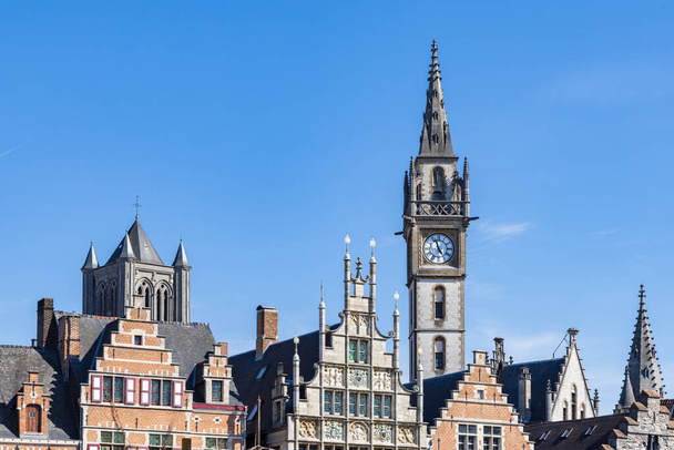 Ancient gable houses and clock tower along the Korenlei in Ghent port city in northwest Belgium during a sunny day - Fotó, kép