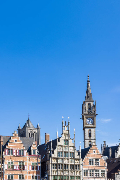 Antiguas casas a dos aguas y torre del reloj a lo largo del Korenlei en la ciudad portuaria de Gante en el noroeste de Bélgica durante un día soleado - Foto, imagen