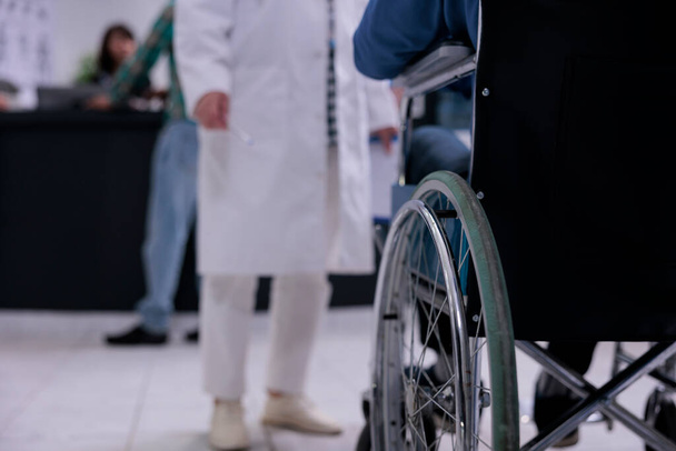 Gros plan de l'homme utilisant un fauteuil roulant devant un médecin à la réception de l'hôpital privé pour un contrôle de routine. Concentration sélective sur les personnes âgées vivant avec un handicap à la réception de la clinique pour rendez-vous. - Photo, image