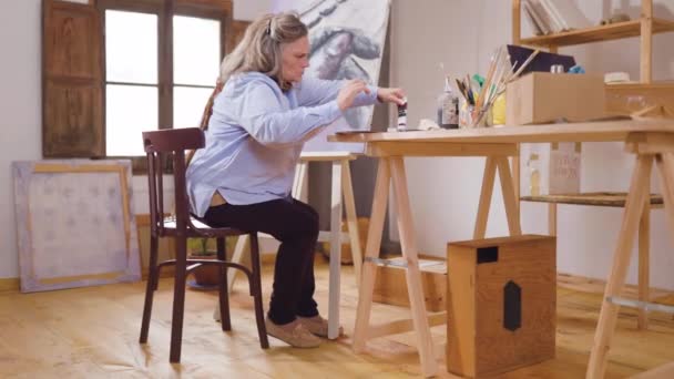 Sanatçı olgun kadın boş zamanlarını atölyesinde resim becerilerini geliştirmeye harcıyor. - Video, Çekim
