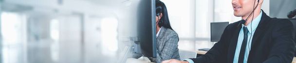 Call center of customer support agent in verbreed zicht panorama banner dragen headset tijdens het werken op kantoor ter ondersteuning van externe klant of collega op telefoon video conference call - Foto, afbeelding