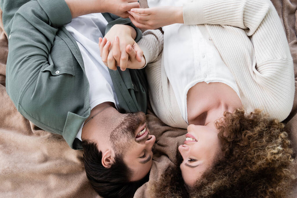 top view of happy young woman and man lying on soft blanket  - Foto, Bild