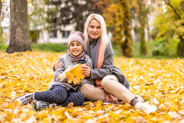 Mother and daughter in autumn yellow park - Photo, Image
