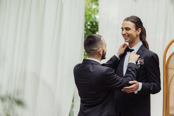 gay man adjusting bow tie on suit of happy groom in formal wear - Valokuva, kuva