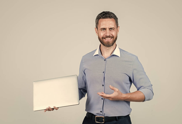 happy mature ambitious man businessman in shirt has grizzled beard presenting product of modern wireless laptop, modern technology. - Zdjęcie, obraz
