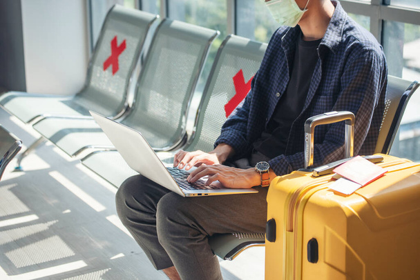 Ázsiai fiatalember utazó új normális laptopot visel arc maszkot ül társadalmi távolság Airplane lounge. Új, normális férfi járvány utas repülővel. Új normál turistaút - Fotó, kép