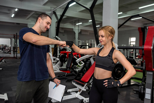 young girl is engaged in a weight training machine in the gym at the most promising coach in the city. The concept of strength training in the gym - Foto, immagini