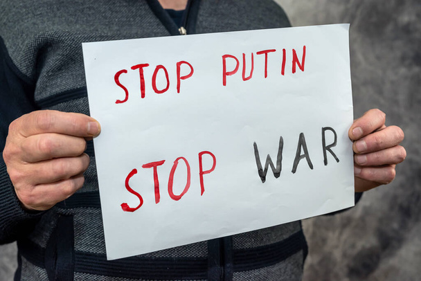 manos masculinas sosteniendo pancarta con la inscripción stop putin. Rusia al agresor y al teórico internacional  - Foto, imagen