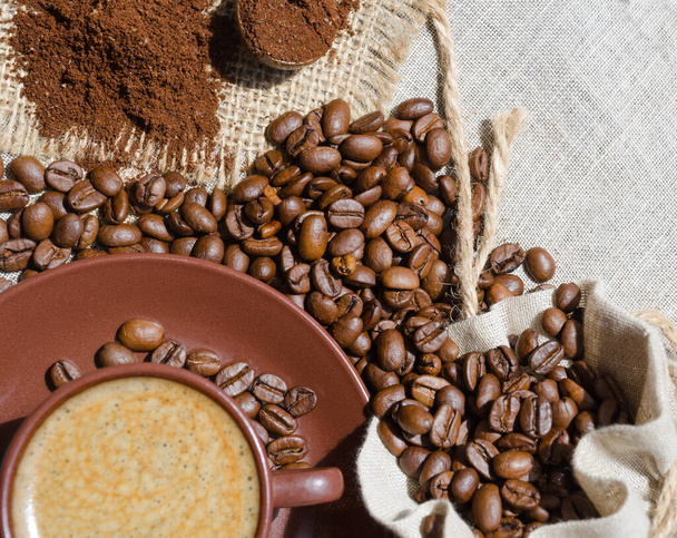 Καφές εσπρέσο σε φόντο καφέ και αλεσμένων φασολιών σε λινάτσα. Arabica είναι ο πιο συνηθισμένος τύπος καφέ. - Φωτογραφία, εικόνα