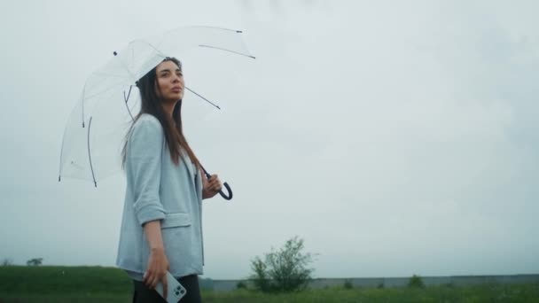 Smutna Ormianka spaceruje w deszczu z parasolem. Lubi tę pogodę. - Materiał filmowy, wideo