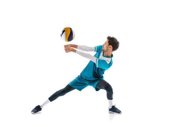 Portrait of young man, volleyball player in motion, training, playing isolated over white studio background. Concept of sport, action, team game, active lifestyle, health, hobby, ad - Foto, afbeelding