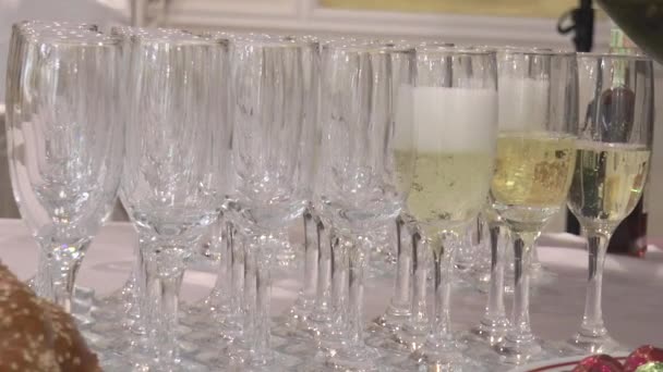 sklenice šampaňského na stole, zpola naplněné šampaňským z láhve zpomaleným pohybem. - Záběry, video