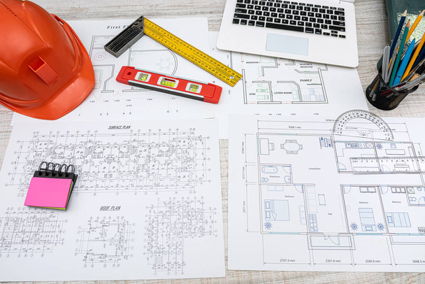 Bauplan mit Reparaturwerkzeug, Helm auf dem Schreibtisch. Immobilien- und Wohnungskonzept - Foto, Bild