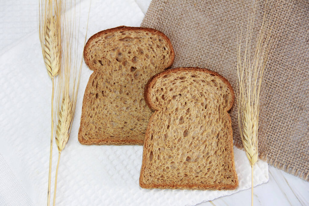 квадратные кусочки ржаного хлеба и сухие колосья пшеницы - Фото, изображение