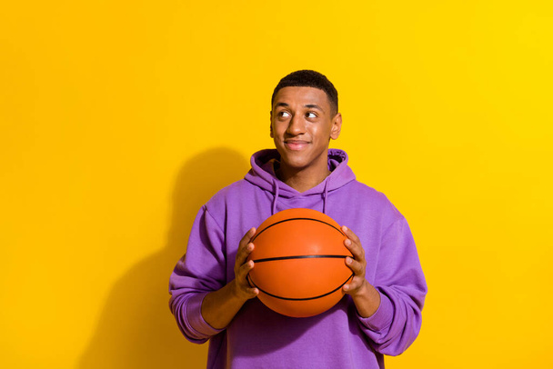 Portrait of attractive professional sportive guy playing basketball isolated over bright yellow color background. - Foto, Imagem