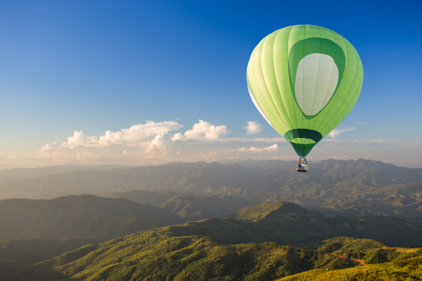 Gün batımında dağ üzerinde yeşil sıcak hava balonu - Fotoğraf, Görsel