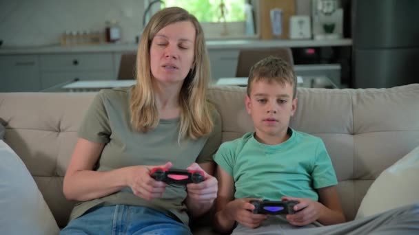 Сын и мать играют дома в видеоигры, Семья проводит время вместе, Счастливые отношения, Онлайн развлечения и досуг, - Кадры, видео