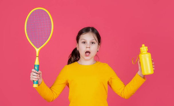 amazed kid hold tennis racket and water bottle on pink background. - Foto, Imagen