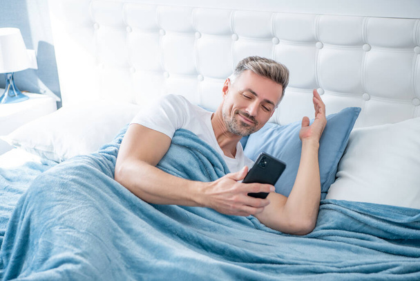 happy mature man in bed chatting on phone. - Фото, зображення