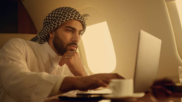 Pensive CEO rozwiązywanie problemów na podróż służbową zbliżenie. Skupiony arabski komputer do pisania na laptopie. Biznesmen sprawdzający pisanie maili. Uśmiechnięty człowiek sukcesu przeglądania Internetu na czacie online w jet - Zdjęcie, obraz