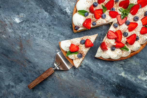 piece of tasty cake pie tart with fresh strawberries, raspberries, blueberry with shovel. Restaurant menu, dieting, cookbook recipe top view. - Fotó, kép