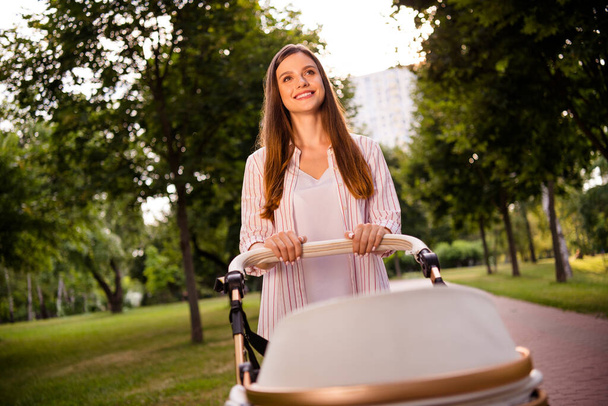 Photo of peaceful satisfied lady have good mood walking baby stroller weekend free time outdoors. - Фото, зображення