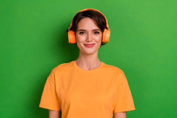 Photo of funky cheerful young lady wear orange outfit headphones enjoying songs isolated green color background. - Fotó, kép