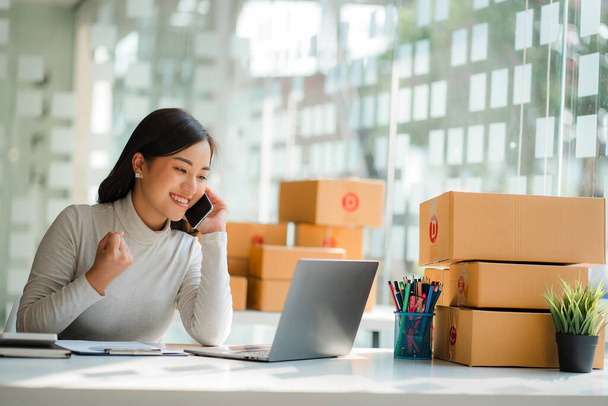 kisvállalkozás indítása kkv-k tulajdonosai, sikeres női vállalkozók Dolgozzon laptopokkal és okostelefonokkal átvételi dobozokkal, és ellenőrizze az online megrendeléseket a dobozok elkészítéséhez. a vevőknek történő értékesítés - Fotó, kép