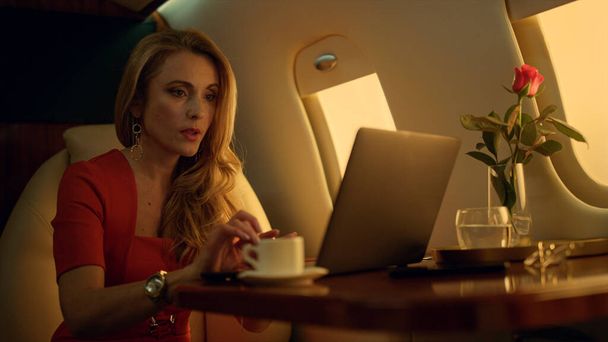 Focused professional work laptop computer closeup. Surprised blonde check email get good news. Satisfied businesswoman enjoy drinking coffee traveling private jet. Attractive woman browsing internet - Photo, Image