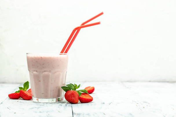 Скло з смачною полуничною коктейлем з ягодами і йогуртом в скляній банці на білому тлі. Вегетаріанський здоровий напій. Місце для тексту. Довгий прапор., - Фото, зображення