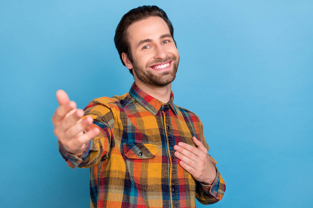 Photo of excited friendly young man wear plaid shirt arm chest inviting you smiling isolated blue color background. - Valokuva, kuva