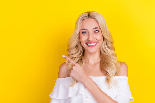 Portrait of attractive cheerful wavy-haired girl demonstrating copy empty space advert isolated over bright yellow color background. - Zdjęcie, obraz