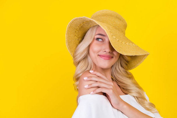 Portrait of attractive cheerful wavy-haired girl wearing straw sunhat touching shoulder isolated over bright yellow color background. - Foto, immagini