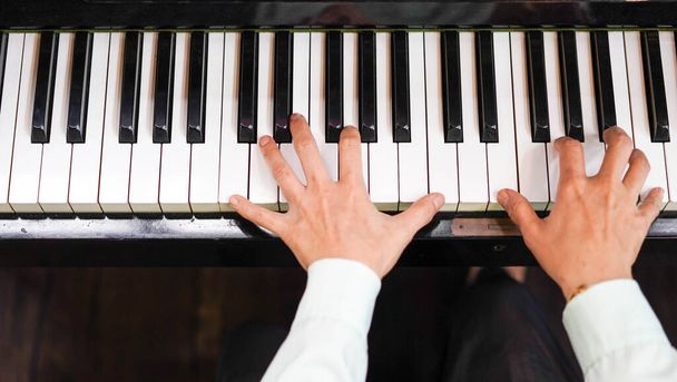 Adult woman plays electronic piano with note sheet. Professional pianist showing solo on acoustic black piano. practicing and learning how to play song. Classic instrument. - 写真・画像